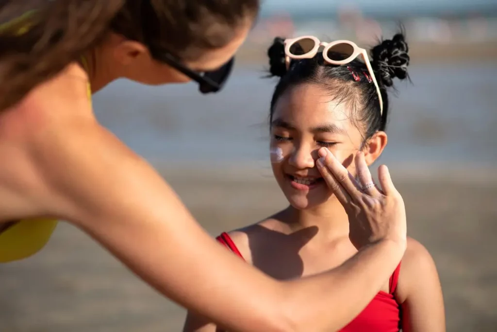 orang yang memakaikan sunscreen pada anaknya